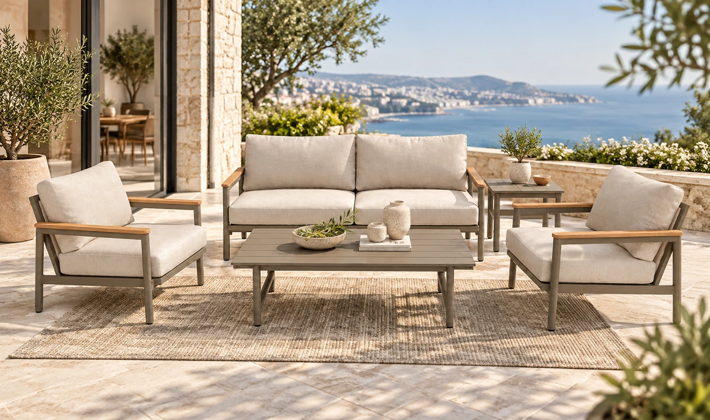 Beige outdoor sofa and matching armchairs surrounding a coffee table on a seaside terrace
